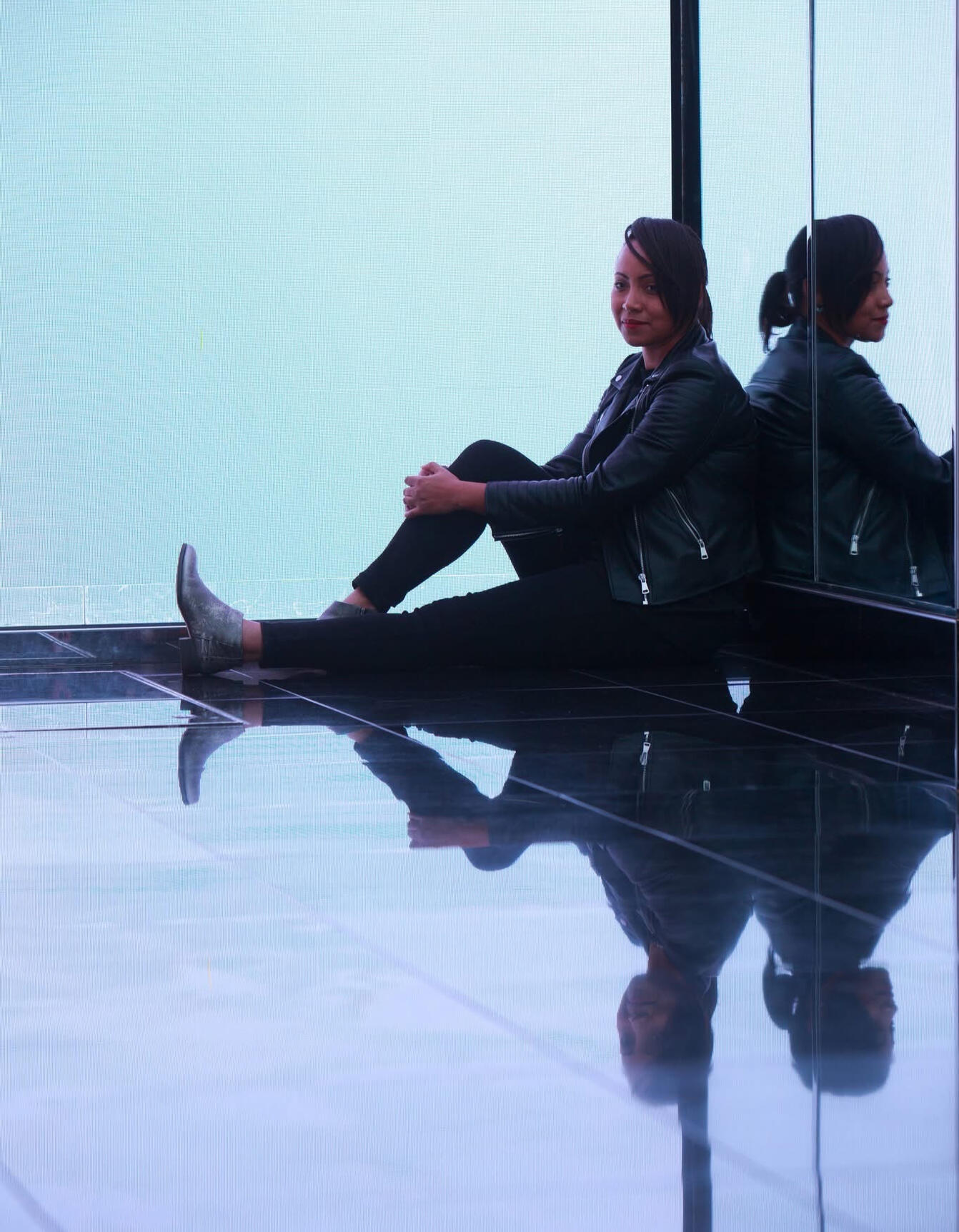 Self portrait sitting by large mirrors.